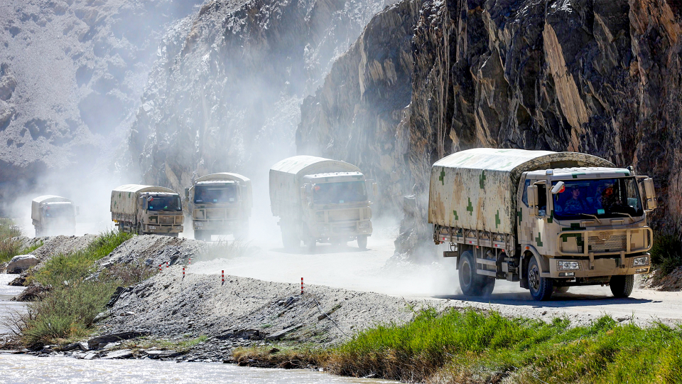 Military vehicles maneuver in valley