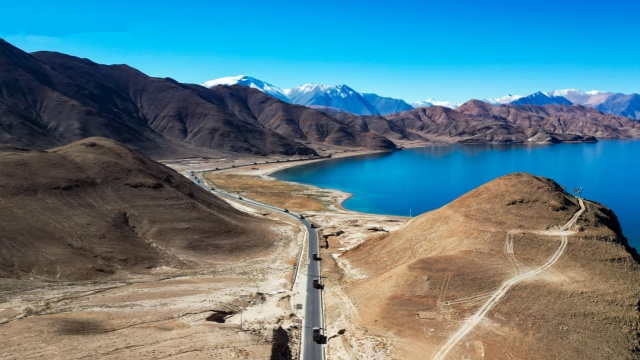 Military trucks snake through snow-clad hills