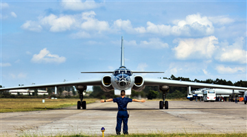 Ground crew member signals to guide bomber