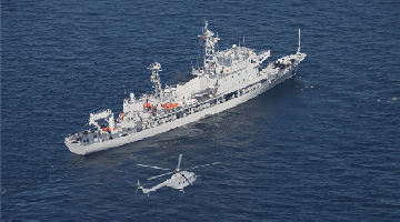 Naval ship and air force helicopter in joint search and rescue training