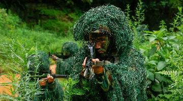 Snipers wearing ghillie suits engage mock targets  