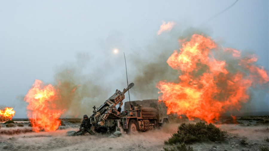 Vehicle-mounted howitzers spit fire down range