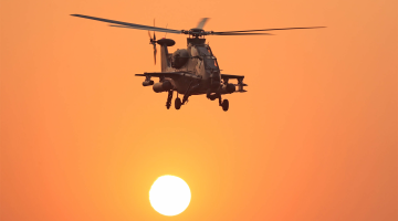 Attack helicopter flies at sunset
