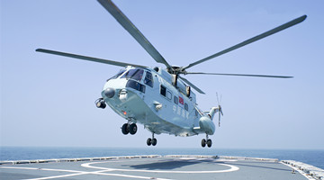 Helicopter coordinates with warship in rescue exercise