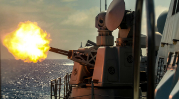 Naval vessels fire at targets during coordination training exercise