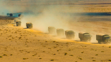 Military vehicles maneuver in desert