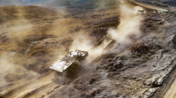 Armored vehicles run in muddy field