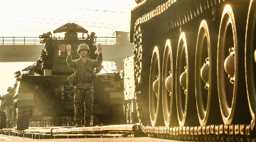 Soldiers load armored vehicles onto rail cars