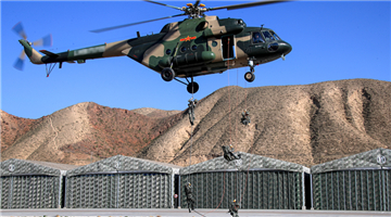 Soldiers fast-rope from hovering helicopters